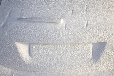 Heck eines Mercedes-AMG vollständig mit Schnee bedeckt, sichtbar sind nur Scheibenwischer und Kennzeichenkontur.
