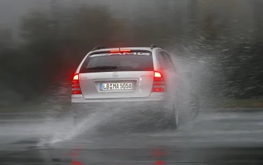 Silberner Mercedes-Benz C 55 AMG T-Modell fährt durch eine Wasserfläche und erzeugt hohe Gischt.