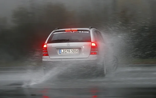 Silberner Mercedes-Benz C 55 AMG T-Modell fährt durch eine Wasserfläche und erzeugt hohe Gischt.