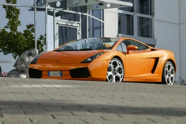 Orangefarbener Lamborghini Gallardo vor einem modernen Gebäude.