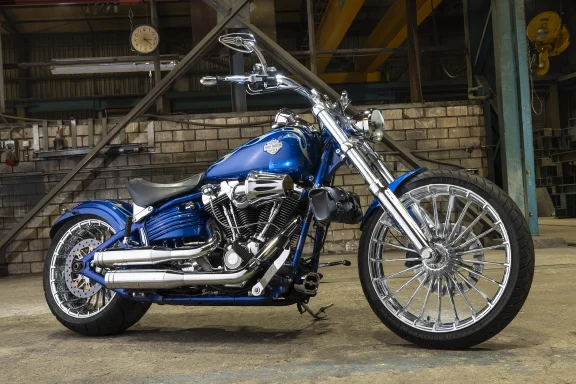 Blaue Harley-Davidson Rocker C FXCWC mit großem Chrom-Vorderrad und Custom-Umbau in einer Industriehalle fotografiert.