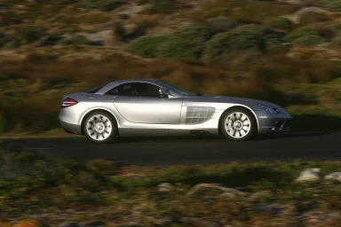 Silberner Sportwagen Mercedes-Mclaren 300 SLR fährt auf einer Landstraße.