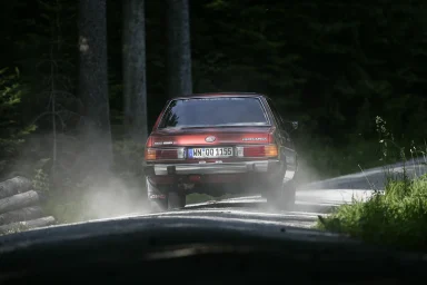 Subaru Leone 1800 4WD von hinten auf einer feuchten Waldstraße in dynamischer Fahrt.