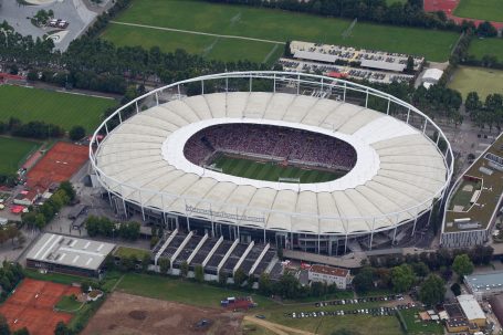 Luftaufnahme eines großen Fußballstadions in Stuttgart mit markanter ovaler Dachkonstruktion.