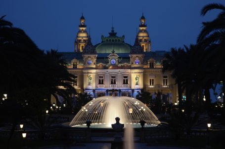 Casino Monte-Carlo in Monaco bei Nacht mit beleuchteter Fassade und Brunnenanlage.