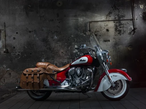 Indian Vintage in rot-weißer Zweifarblackierung mit braunen Lederkoffern vor Industriehintergrund.
