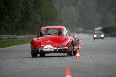 Mercedes-Benz 300 SL Flügeltürer auf nasser Fahrbahn im Starkregen während eines Slalomparcours.