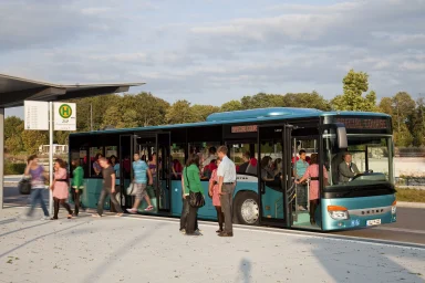 Türkiser Setra S415NFLinienbus steht an einer Bushaltestelle, während Fahrgäste ein- und aussteigen.