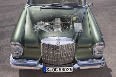 Frontansicht einer grünen Mercedes-Benz Heckflosse mit durchsichtiger Motorhaube und sichtbarem Motorraum.