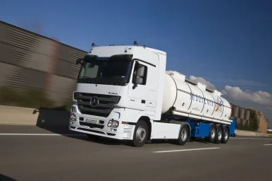 Weißer Mercedes-Benz Actros 1848 mit Silotankauflieger für den Zuckertransport fährt auf einer Autobahn.