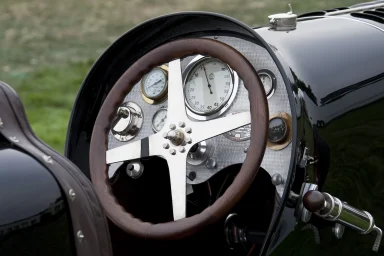 Cockpit eines Bugatti Type 35 mit Holzlenkrad und historischen Rundinstrumenten.
