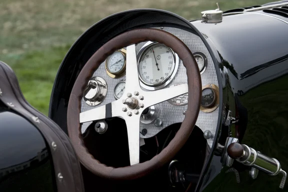 Cockpit eines Bugatti Type 35 mit Holzlenkrad und historischen Rundinstrumenten.
SEO-Dateiname: