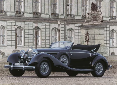 Schwarzer Oldtimer-Cabrio vor einer historischen Kulisse mit Skulpturen.