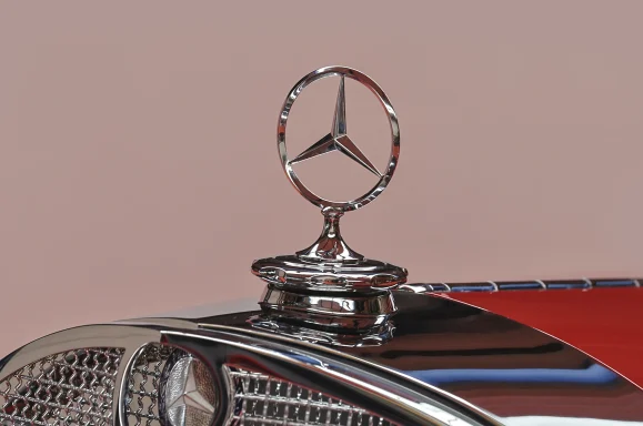 Detailaufnahme des Mercedes-Benz Kühlersterns auf der Motorhaube eines roten Mercedes-Benz 540 K.

