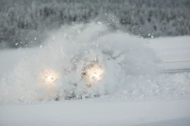 Fahrzeug bei der Wintererprobung in Arjeplog verschwindet fast vollständig in einer aufgewirbelten Schneewolke.