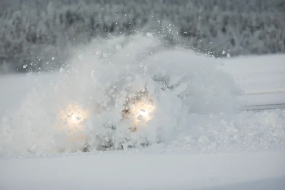 Fahrzeug bei der Wintererprobung in Arjeplog verschwindet fast vollständig in einer aufgewirbelten Schneewolke.