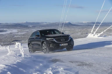 Schwarzer Mercedes-Benz EQC 400 4MATIC auf verschneiter Bergstraße mit winterlicher Landschaft und schneebedeckten Bergen im Hintergrund.