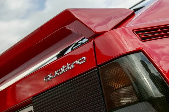 Detailaufnahme von Heckspoiler und quattro-Emblem am Audi Urquattro.
