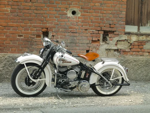 Harley-Davidson WLA von 1942 in cremeweißer Lackierung mit Ledersattel und Weißwandreifen vor einer historischen Backsteinfassade.