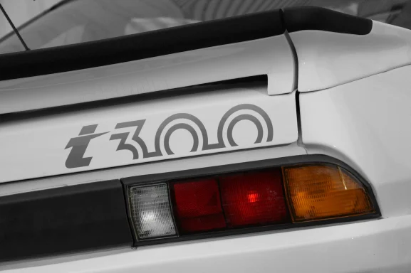 Nahaufnahme des Hecks eines weißen Irmscher Manta i300 mit Typenschriftzug, Heckspoiler und Rückleuchten.