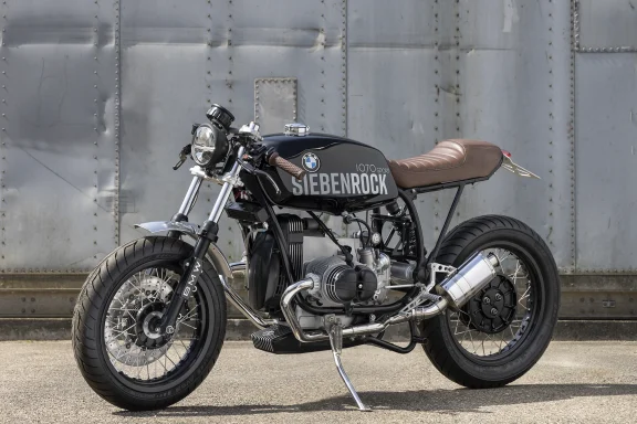 BMW R100 Café Racer von Siebenrock mit 1070 Sport-Motor vor einer Metallwand fotografiert.