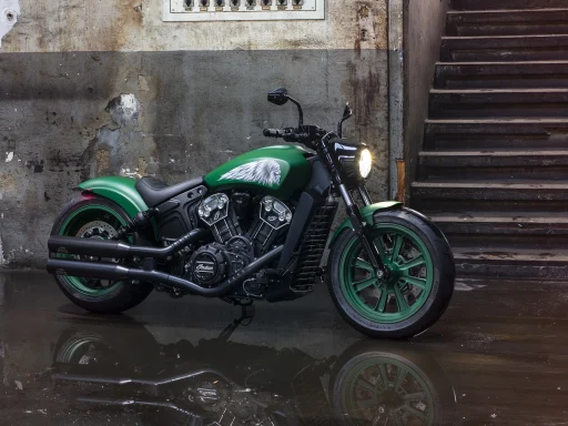 Individuell gestaltete Indian Scout Custom in Grün vor markanter Industriekulisse.
