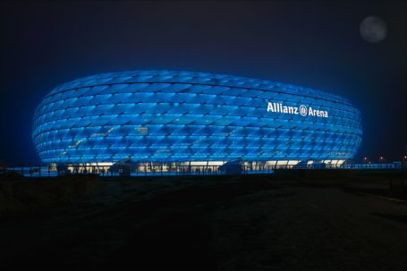 Allianz Arena München bei Nacht mit blau beleuchteter Außenhülle.