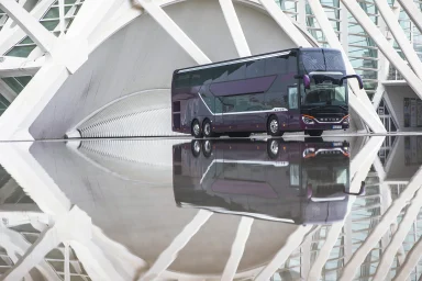 Setra S 531 DT Doppeldecker-Reisebus steht vor moderner Architektur und spiegelt sich auf einer glänzenden Fläche.