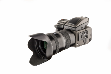 Hasselblad Mittelformatkamera HD50 mit angesetztem Objektiv und Gegenlichtblende als freigestellte Produktaufnahme auf hellem Hintergrund.