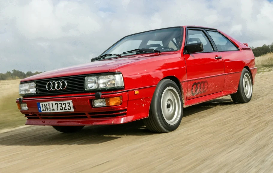 Audi Ur-quattro in voller Fahrt Roter Audi Ur-quattro durchquert eine Wasserpassage und erzeugt eine hohe Gischt.