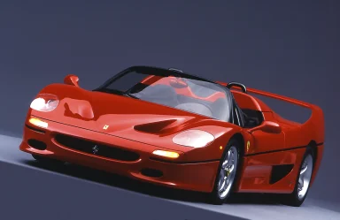 Roter Ferrari F50 in Dreiviertelansicht vor dunklem Studiohintergrund mit geöffnetem Dach und integriertem Heckflügel.