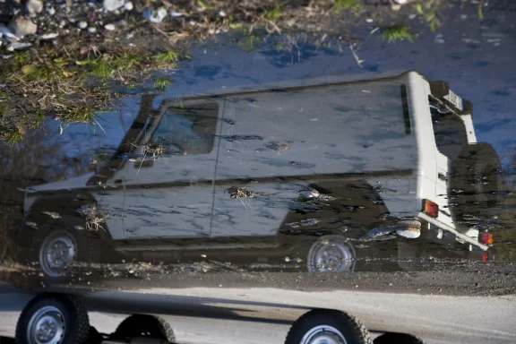 Spiegelung eines Mercedes-Benz G-Modells in einer Pfütze mit abstrakten Reflexionen und natürlichen Strukturen.