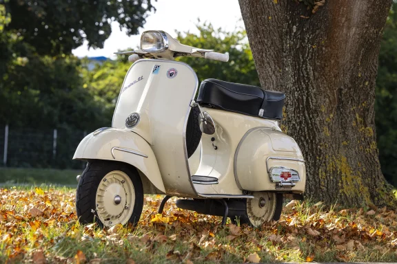 Cremefarbene Vespa GL 150 Baujahr 1963 unter einem alten Baum im Herbst.
