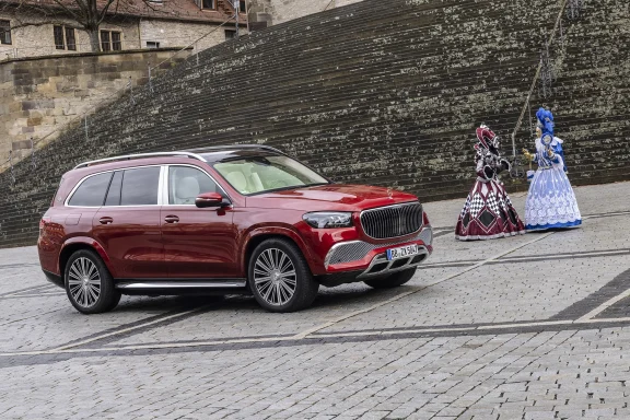 Roter Mercedes-Maybach GLS 600 auf einem historischen Platz vor großer Steintreppe, daneben zwei Personen in venezianischen Kostümen.