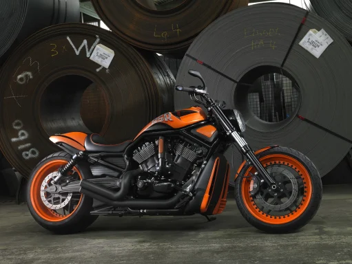 Harley-Davidson VRSCDX Night Rod Special von 2010 in Orange und Schwarz vor großen Stahlcoils.
