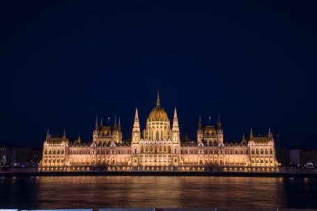 Ungarisches Parlamentsgebäude in Budapest bei Nacht mit Spiegelung in der Donau.