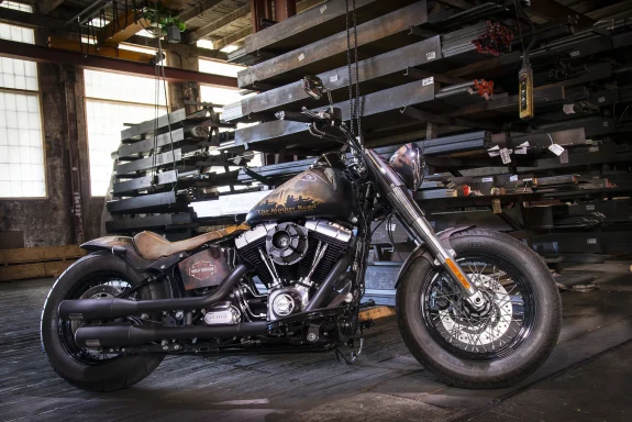 Harley-Davidson Softail Slim FLS von 2013 mit Route-66-Design vor Stahlprofilen in einer Industriehalle.