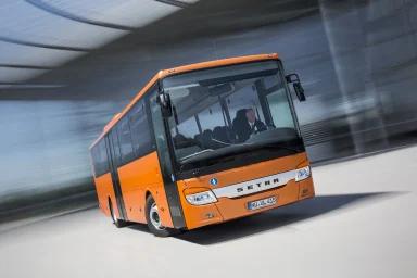 Oranger Setra S 415 UL Linienbus in dynamischer Fahrt mit Bewegungsunschärfe im Hintergrund.