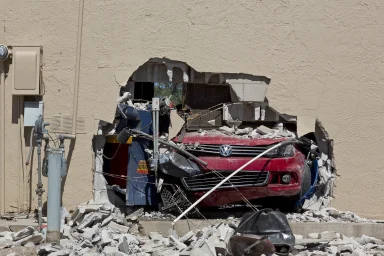 Roter Volkswagen steckt nach einem Unfall in einer Hauswand.