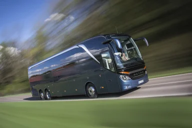 Dunkelblauer Setra Setra S 516 HDH Reisebus in Bewegung auf einer Landstraße mit verwischtem Hintergrund und grüner Landschaft.