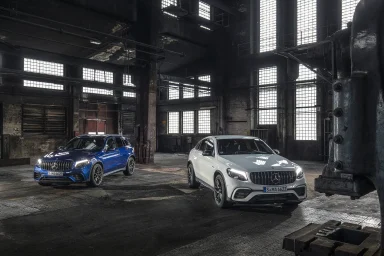 Zwei Mercedes SUV, ein blauer und ein weißer SUV, stehen in einer alten Fabrikhalle.