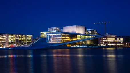 Opernhaus Oslo am Oslofjord bei Nacht mit beleuchteter Architektur und Spiegelung im Wasser.