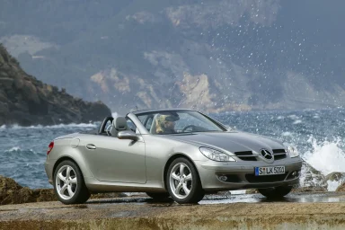 Mercedes-Benz SLK Roadsterparkend an der Küste mit Wellen im Hintergrund.