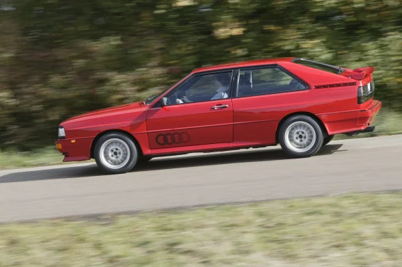Roter Audi Urquattro in schneller Fahrt auf einer  Landstraße.
