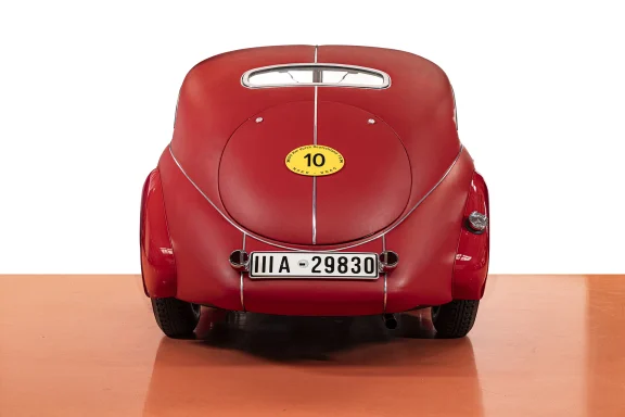 Heckansicht eines roten Mercedes-Benz 540 K Stromlinien-Coupés mit charakteristischer aerodynamischer Karosserie vor neutralem Hintergrund.
