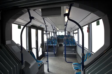 Innenraum eines modernen Gelenkbusses mit Sitzplätzen und Haltestangen.
