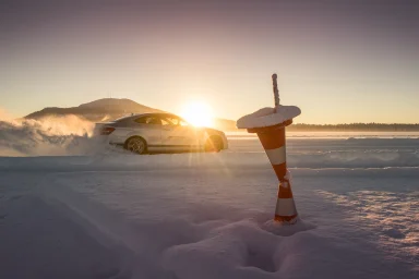 Mercedes-AMG bei der Wintererprobung auf einer verschneiten Teststrecke in Arjeplog mit tief stehender Sonne und vereister Pilone.