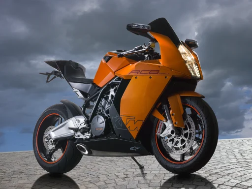 Orange KTM RC8 1190 Sportmotorrad auf Kopfsteinpflaster vor dunklem Wolkenhimmel.
