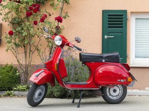 Rote Vespa PX 200 E Baujahr 1991 vor Hausfassade mit Rosen und Lavendel.
