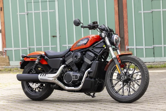 Harley-Davidson Nightster 975T 2026 in Orange und Schwarz mit Revolution Max Motor, fotografiert vor einer historischen Industriekulisse.